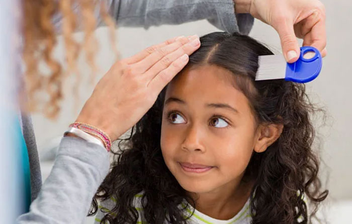 Teacher combing a female student's hair of lice. 